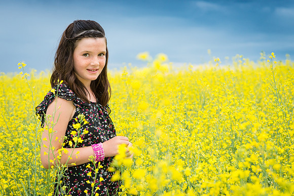 A portrait of a girl standing in a Canola field